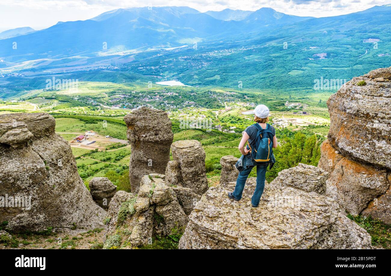 Landschaft der Krim, Russland. Junge Frau auf bizarren Steinen im Tal der Geister. Dieser Ort ist eine Touristenattraktion der Krim. Panoramaaussicht auf So Stockfoto