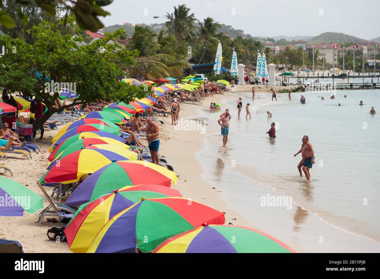 Viel touristische Aktivität und bunte Sonnenschirme, Spaß am Strand an einem beliebten Strand an einem hellen sonnigen Tag Stockfoto