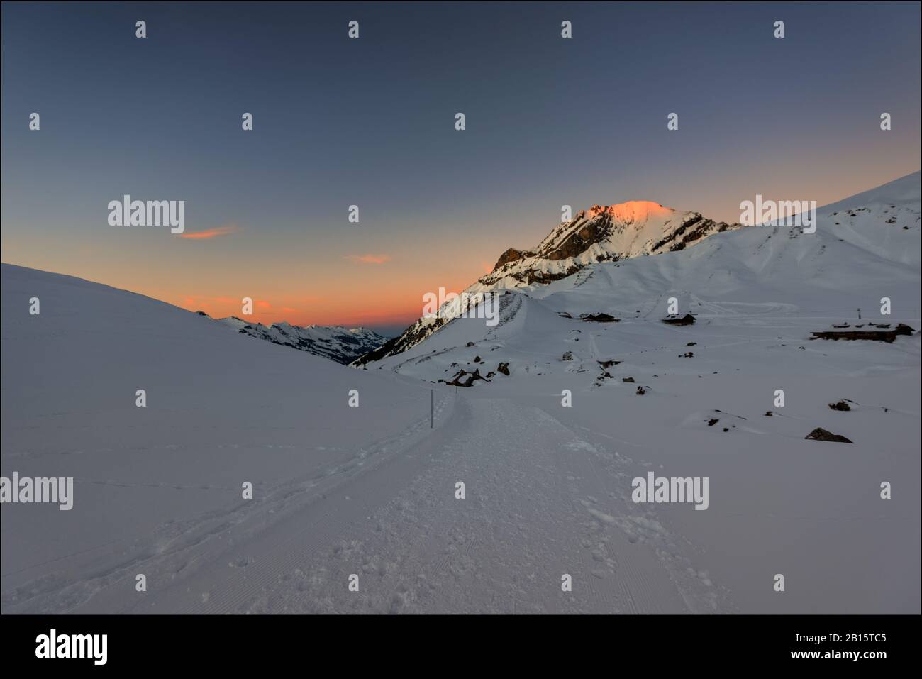 Schneewanderweg bei Engstligenalp, Adelboden, Schweiz zur Blaustunde; sonniger Gipfel des Lohner. Stockfoto