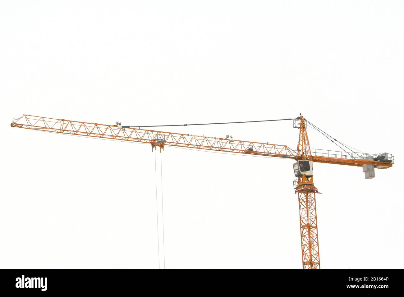 Turmkran arbeitet an einer Baustelle gegen den weißen Himmel im Bau. Stockfoto