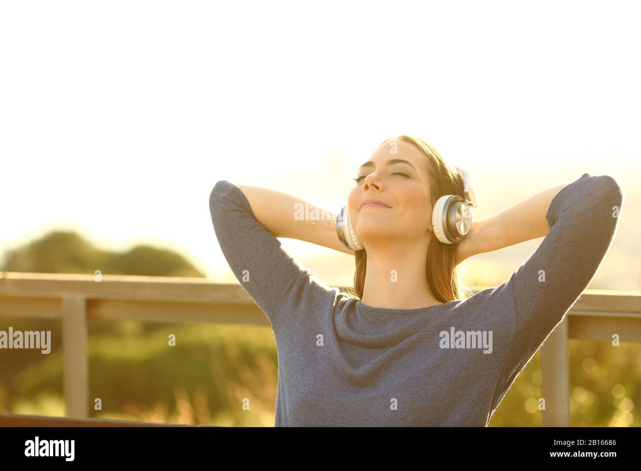 Entspannte junge Frau, die Musik hört und im Freien in der Natur meditiert Stockfoto