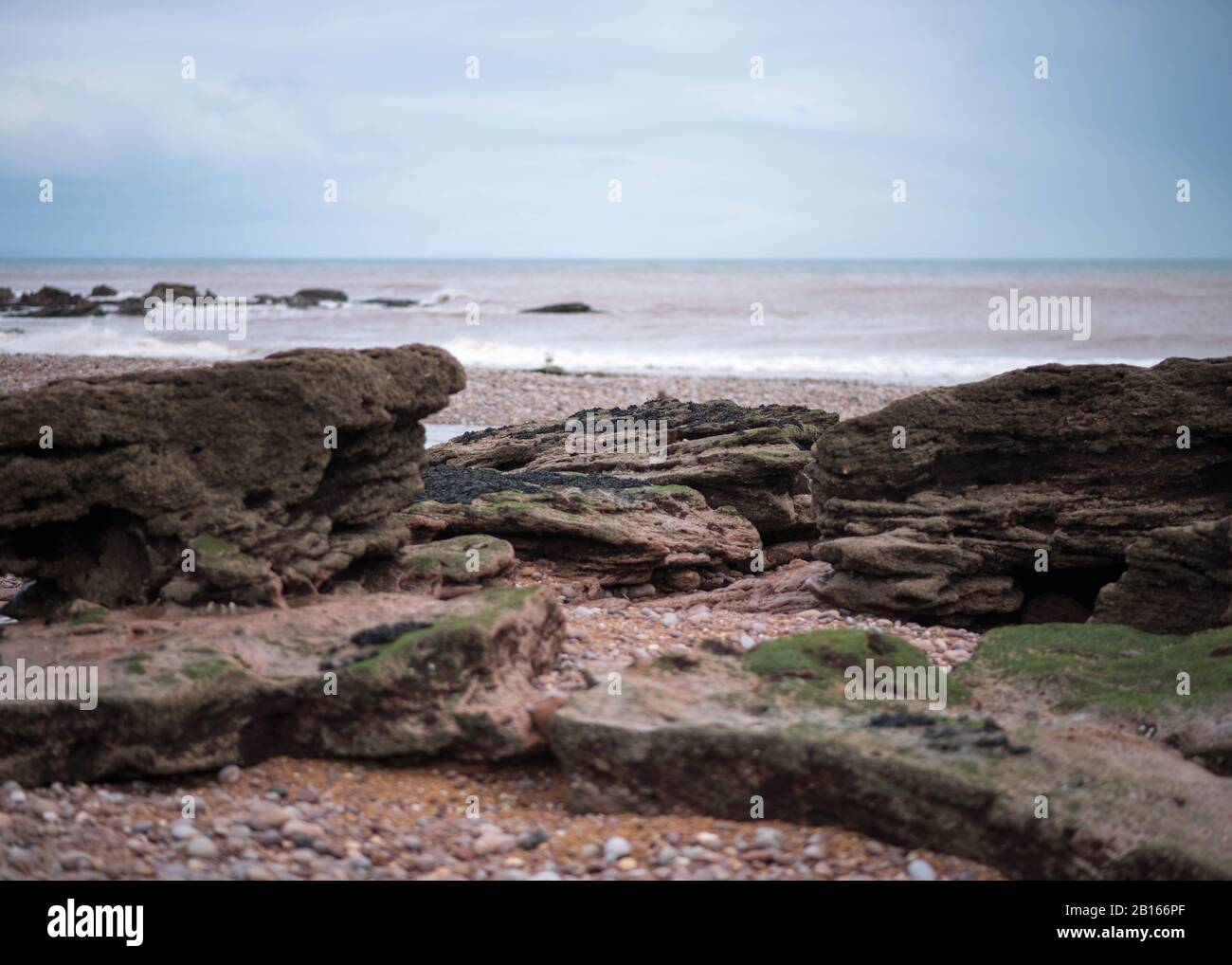 Felsen und Felsenbecken bei Ebbe in Budleigh Salterton in East Devon, England, Großbritannien - Bewölkt Winter Day Stockfoto