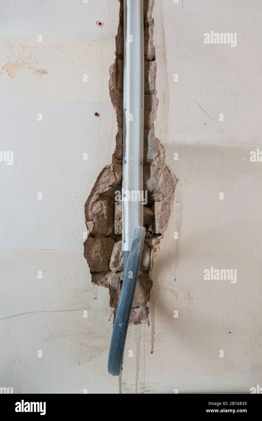 Freiliegende Kabel in einem Kanal in einer Ziegelwand, während ein Raum renoviert wird. Stockfoto