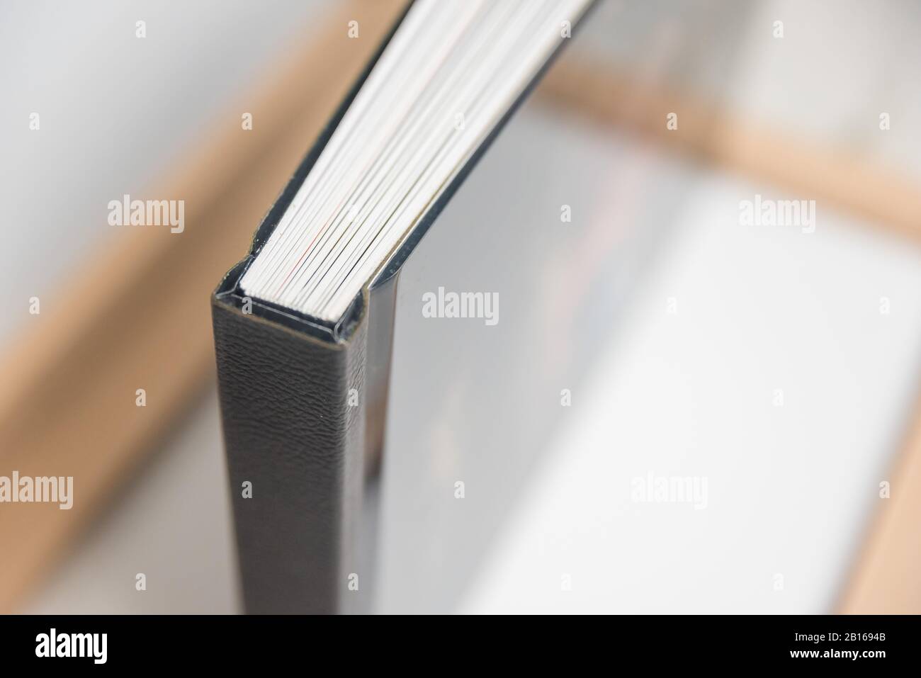 Nahansicht der Bindung von Fotobuchbüchern - Wirbelsäulenansicht des Blocks. Schwarze Lederrücken mit scharfen Ecken oder Kanten. Stockfoto
