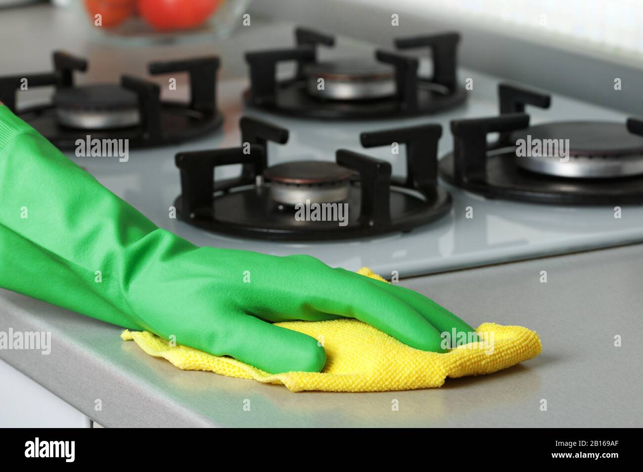 Nahaufnahme einer Hand in einem Schutzhandschuh mit Serviette. Waschen der Arbeitsplatten. Reinigen der Küche. Stockfoto