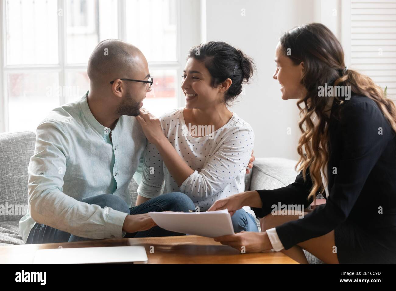 Das multiethnische Paar fühlt sich mit den Verhandlungsergebnissen mit dem Agenten zufrieden Stockfoto