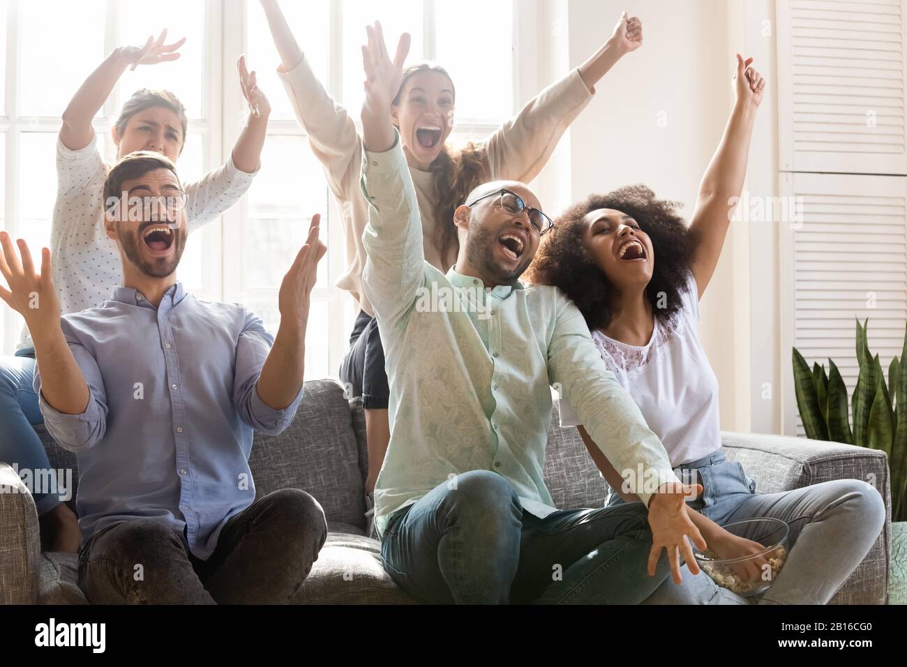 Multirassische Leute, die mit Freude den Sieg des Sportteams feiern Stockfoto