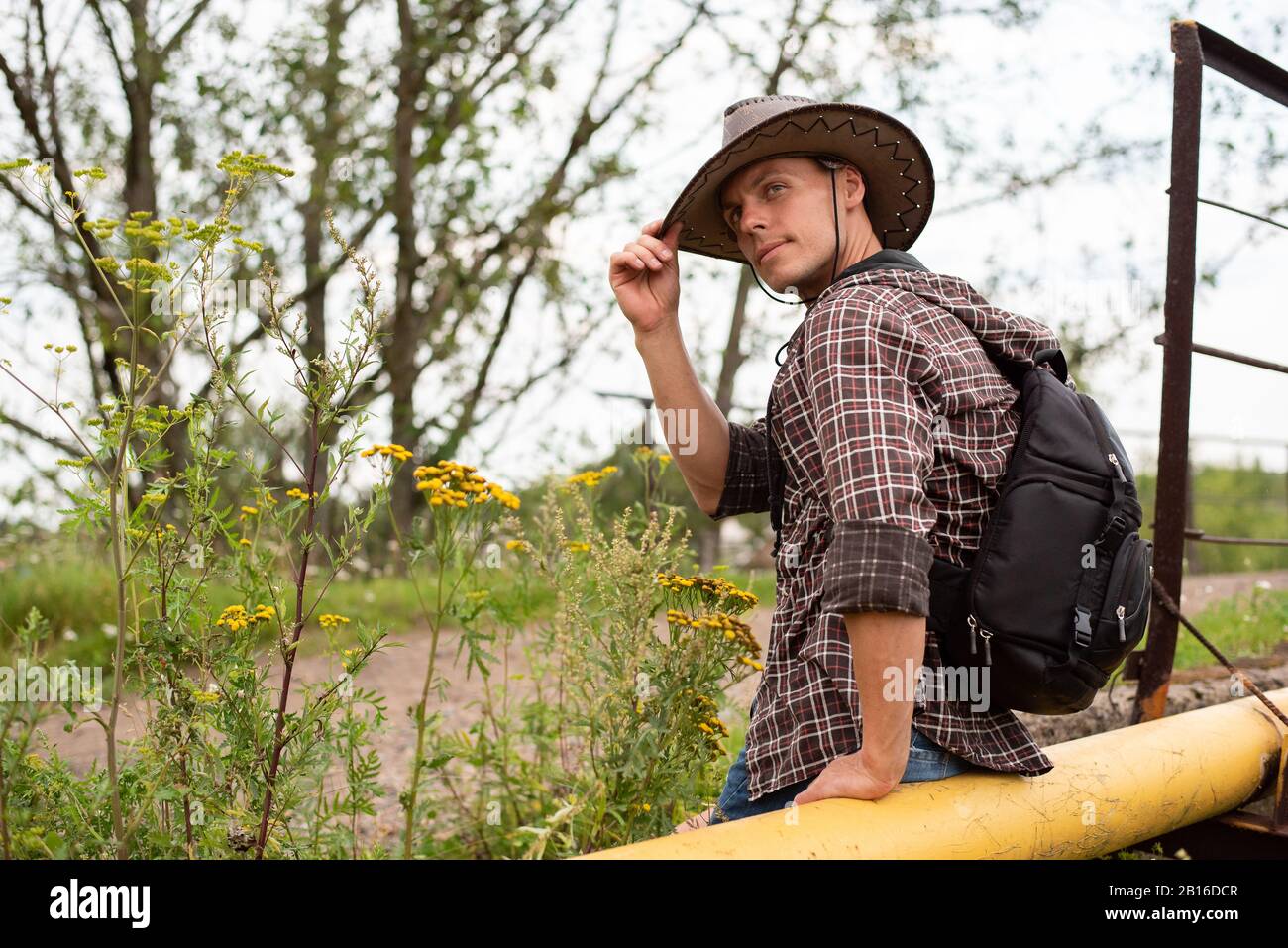 Ein Mann in einem Cowboyhut sitzt auf einer Gasleitung. Stockfoto