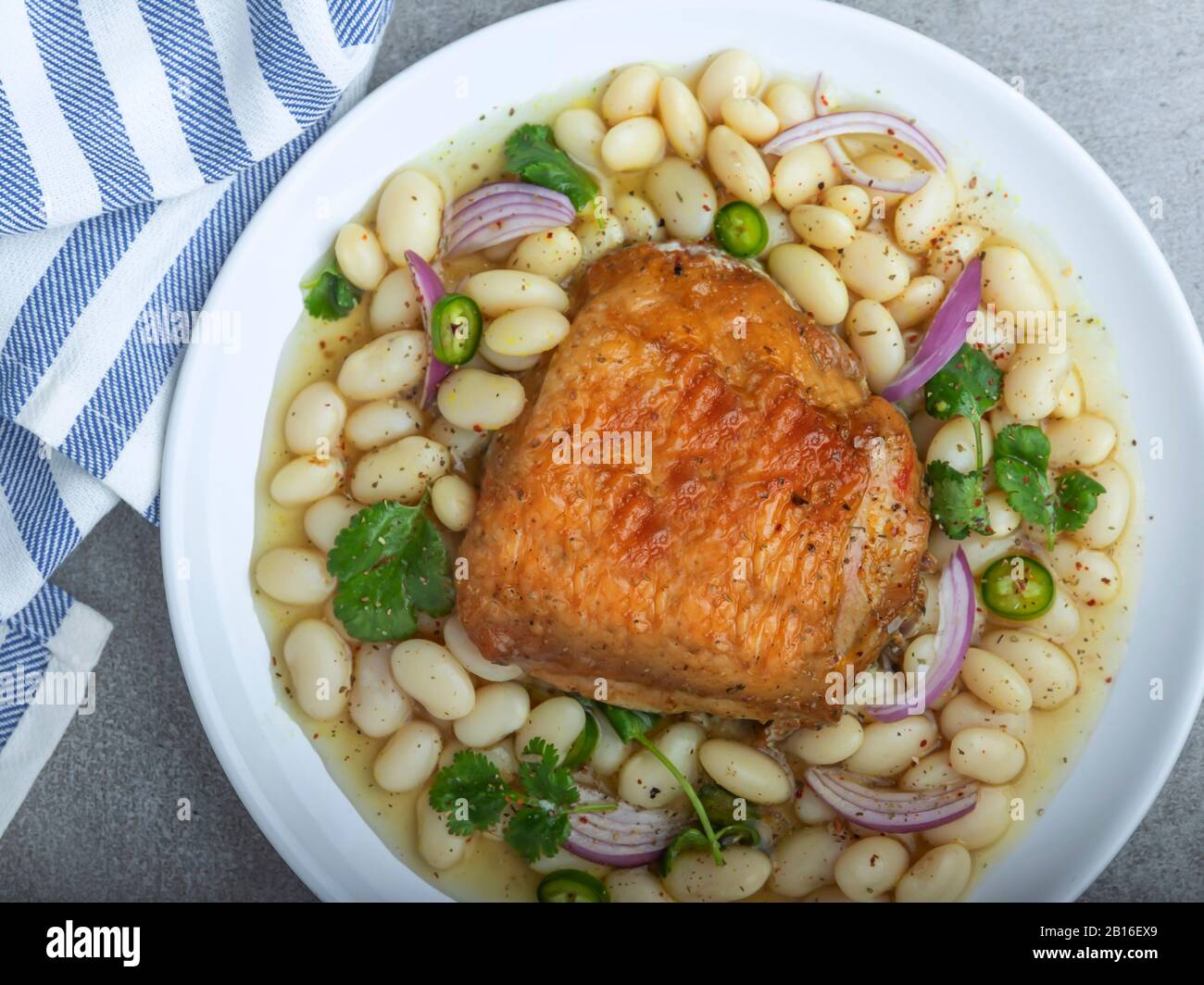 Gebackener Hähnchenschenkel mit weißen Bohnen in Platte Stockfoto