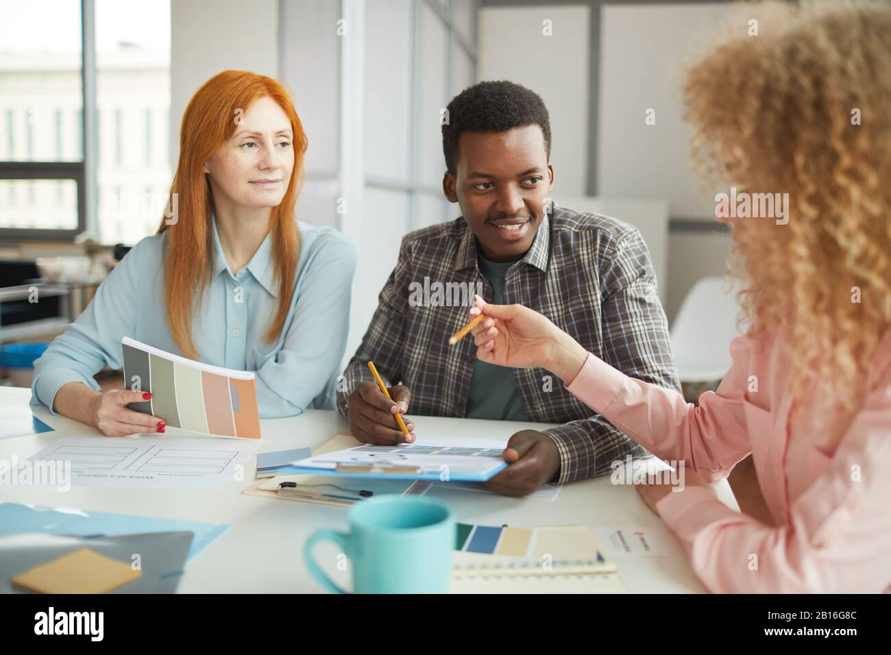 Portrait des jungen afroamerikanischen Mannes, der während eines Treffens mit dem Team im modernen Büro über kreatives Projekt spricht, Copy-Space Stockfoto