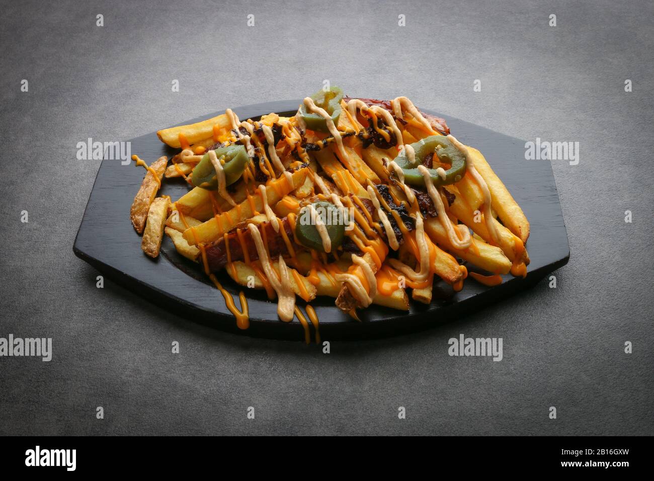 Pommes frites - Pommes frites mit amerikanischem Käse und Cheddar-Käse, Nahaufnahme auf einem Teller. Horizontale Ansicht von oben Stockfoto