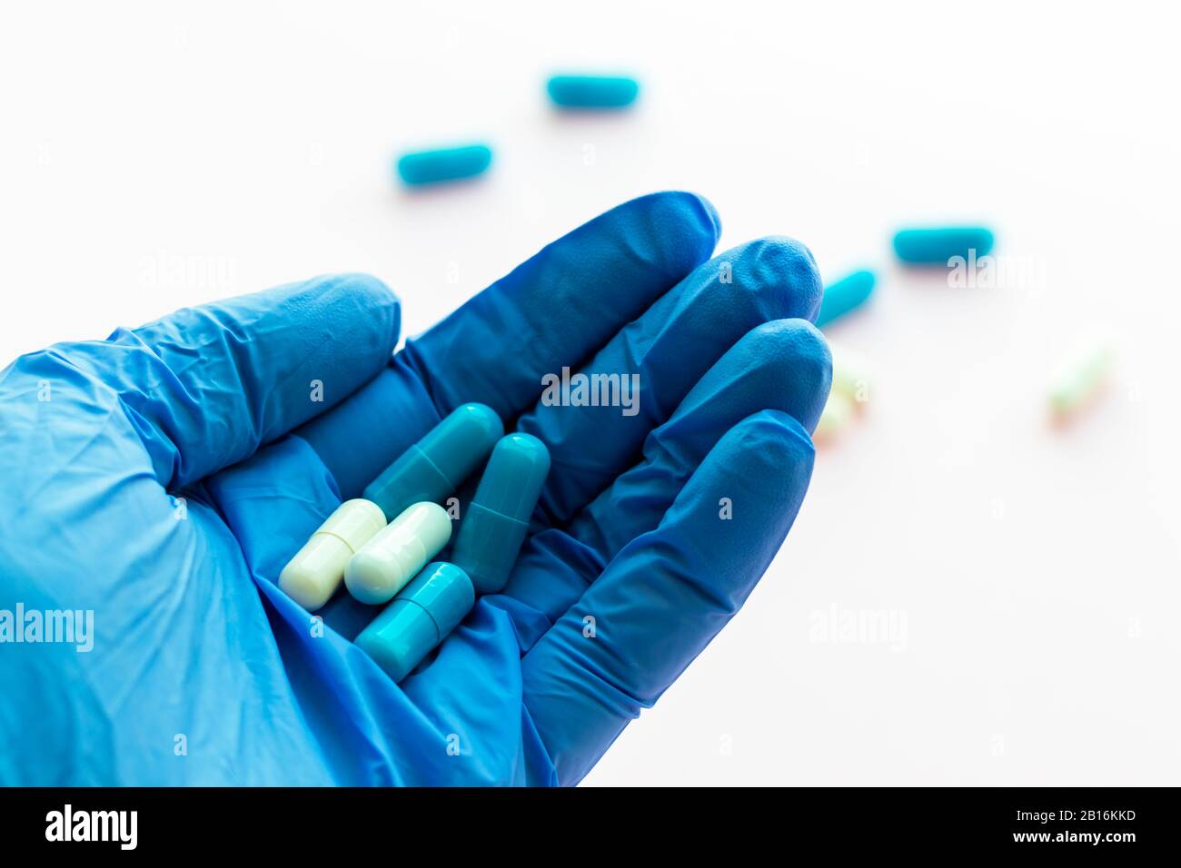 Hand des Arztes in blauem Latexhandschuh mit Kapseln schließen. Legales Drogengeschäft. Verschreibungspflichtige Medikamente. Pharmaindustrie. Epidemie, Schmerzmittel, h Stockfoto