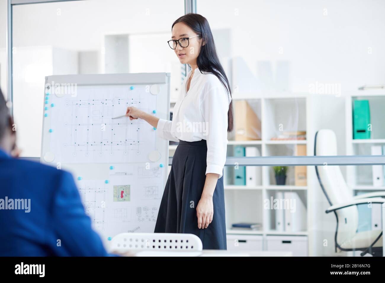 Portrait junger asiatischer Geschäftsfrau, die auf Whiteboard zeigt, während sie während des Meetings im Büro Designprojekt präsentiert, Copy Pace Stockfoto