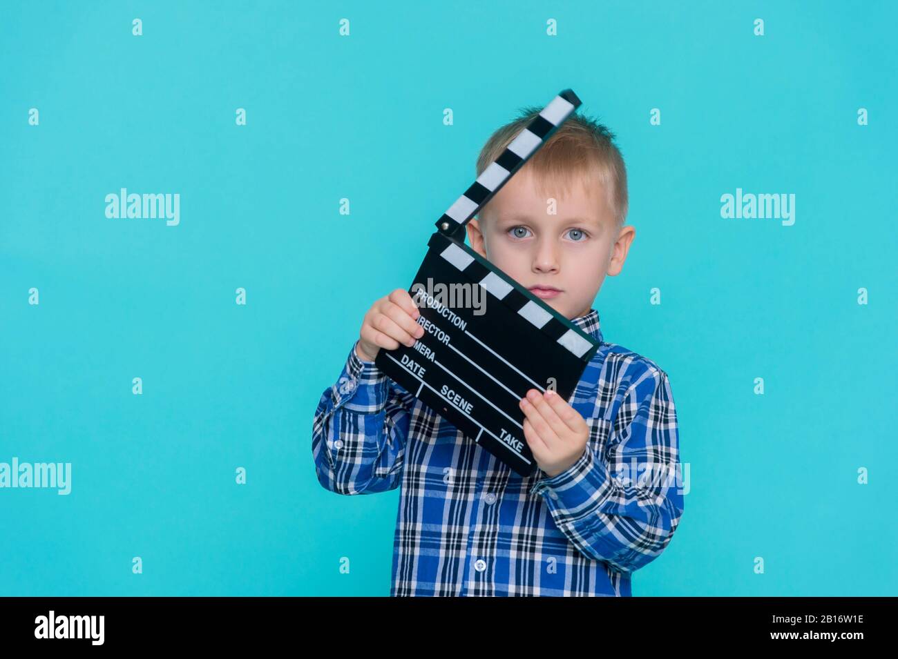 Kind hält Filmklapper-Brett auf blauem Hintergrund Stockfoto