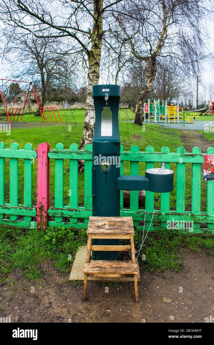 Ein Trinkbrunnen und eine Flaschenfüllstelle außerhalb eines Childspiels befinden sich in Bradford auf Avon Wiltshire mit einem Holzschritt, der daran angekettet ist Stockfoto