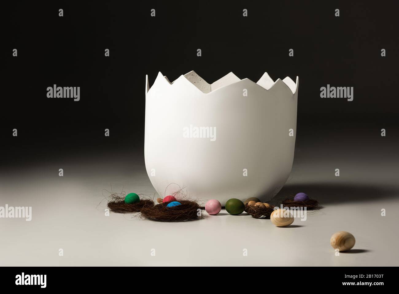 Leere Eggschale neben ostereiern und Nestern auf schwarzem Grund Stockfoto