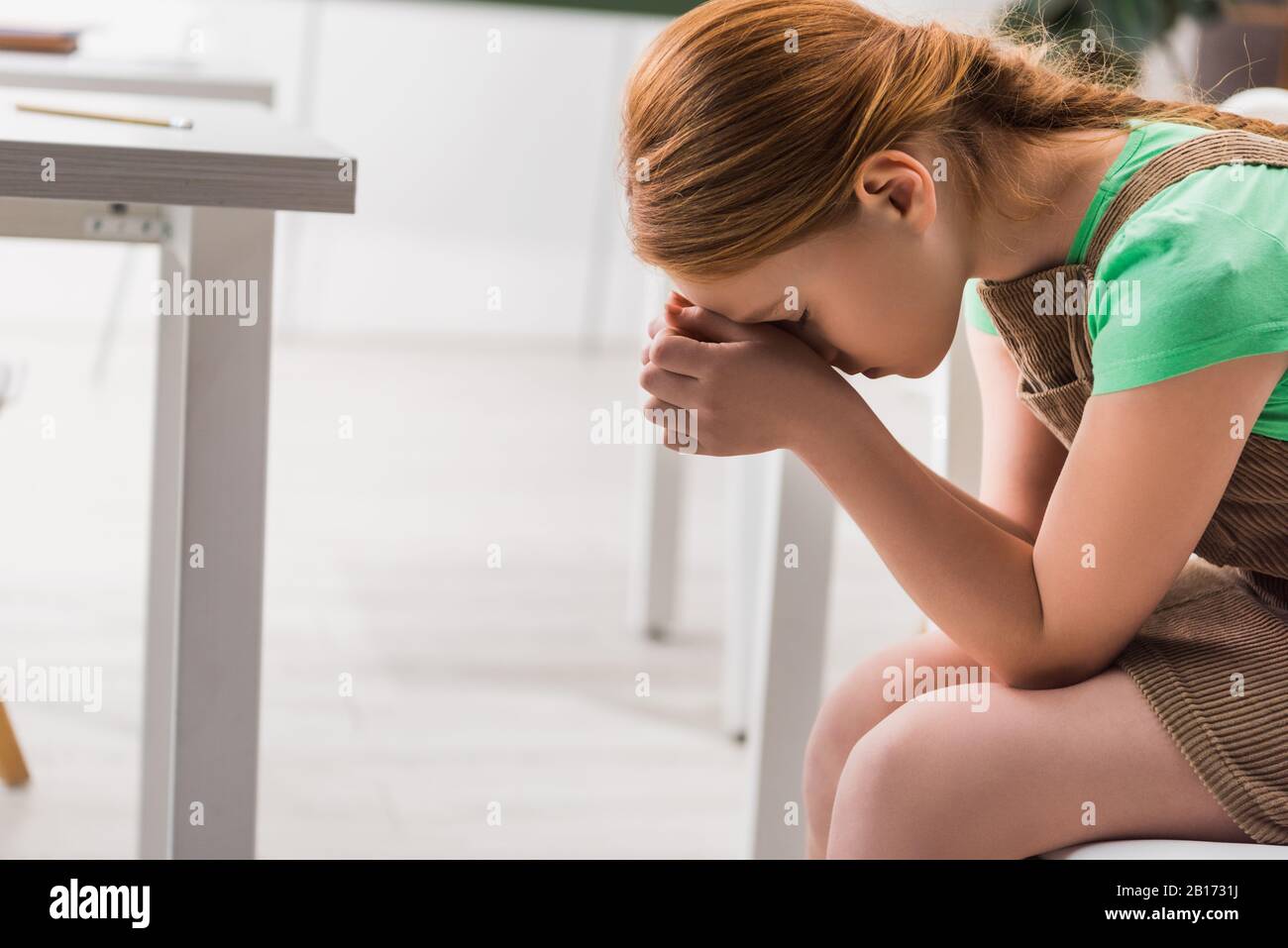 Frustrierte und schikanierte Schulmädchen, die im Klassenzimmer sitzen Stockfoto