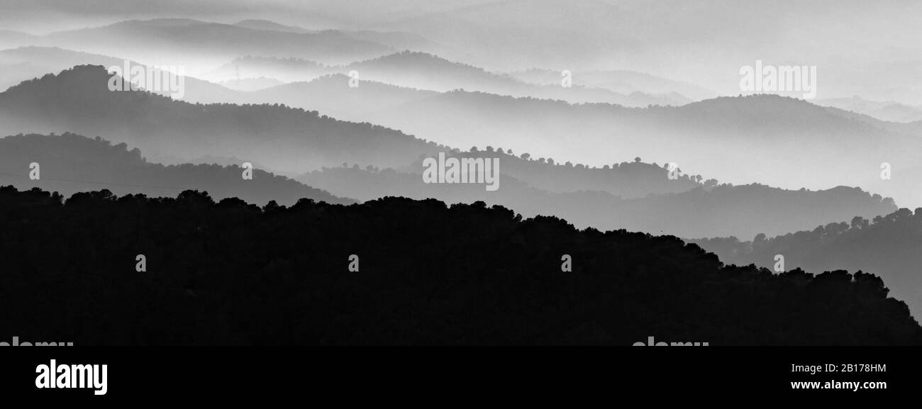 Monochromatische Szene von nebeliger Landschaft von Bergschichten. Nebelige Berge mit Nebel in schwarz-weiß. Stockfoto