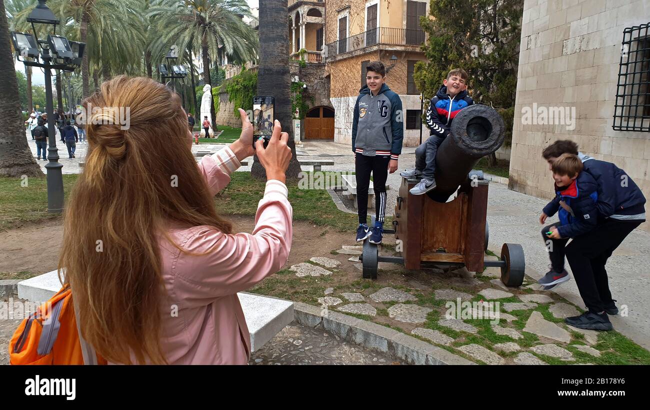 Mutter fotograft ihre Söhne auf einer Kanone in der Altstadt von Alcúdia, Spanien, Balearen, Mallorca, Alcudia Stockfoto