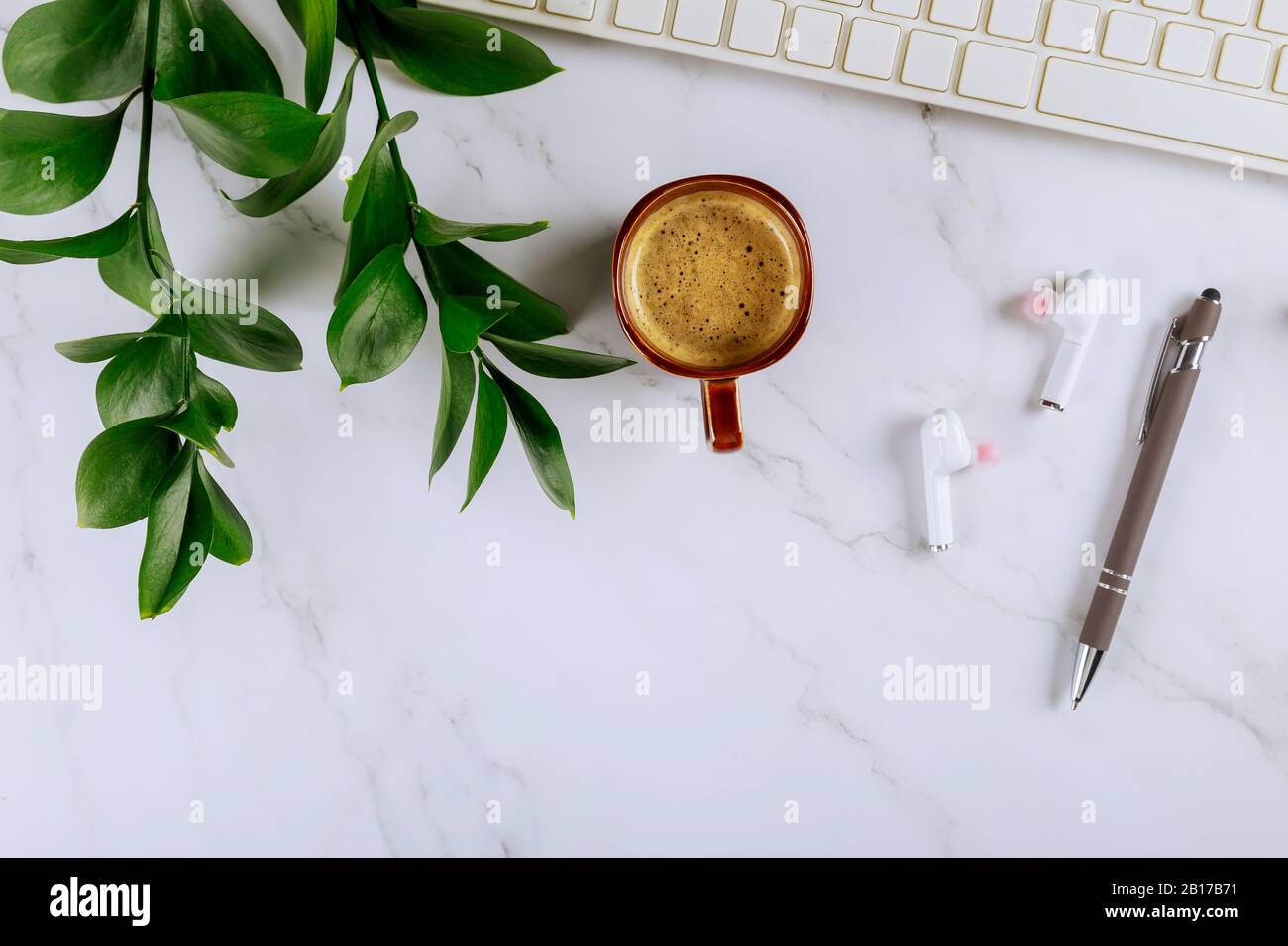 Arbeitsbereich mit Bürozubehör und Zubehör drahtlose Kopfhörer mit Stiftbecher mit Kaffeetastatur Notizblock, Stockfoto
