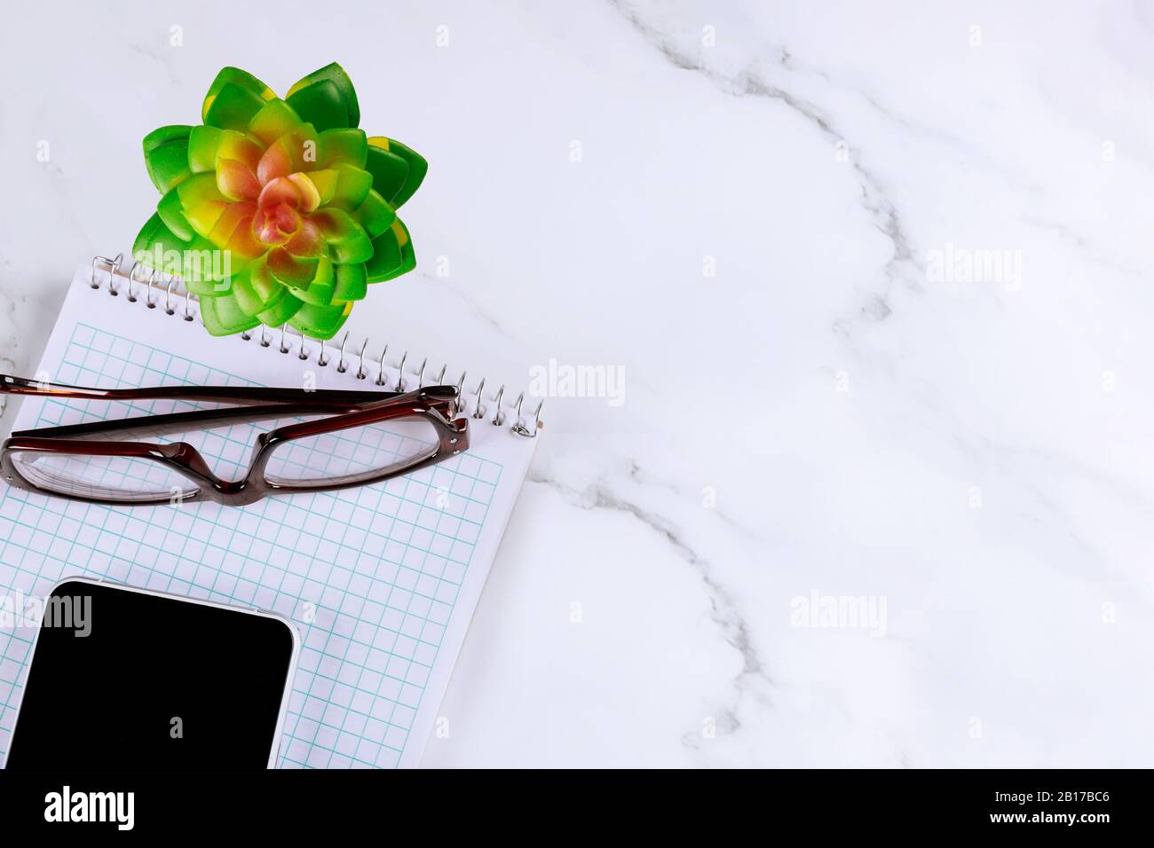 Der elegante Bürotisch mit Bürotisch bietet Smartphone-Notizblock und Brille Stockfoto