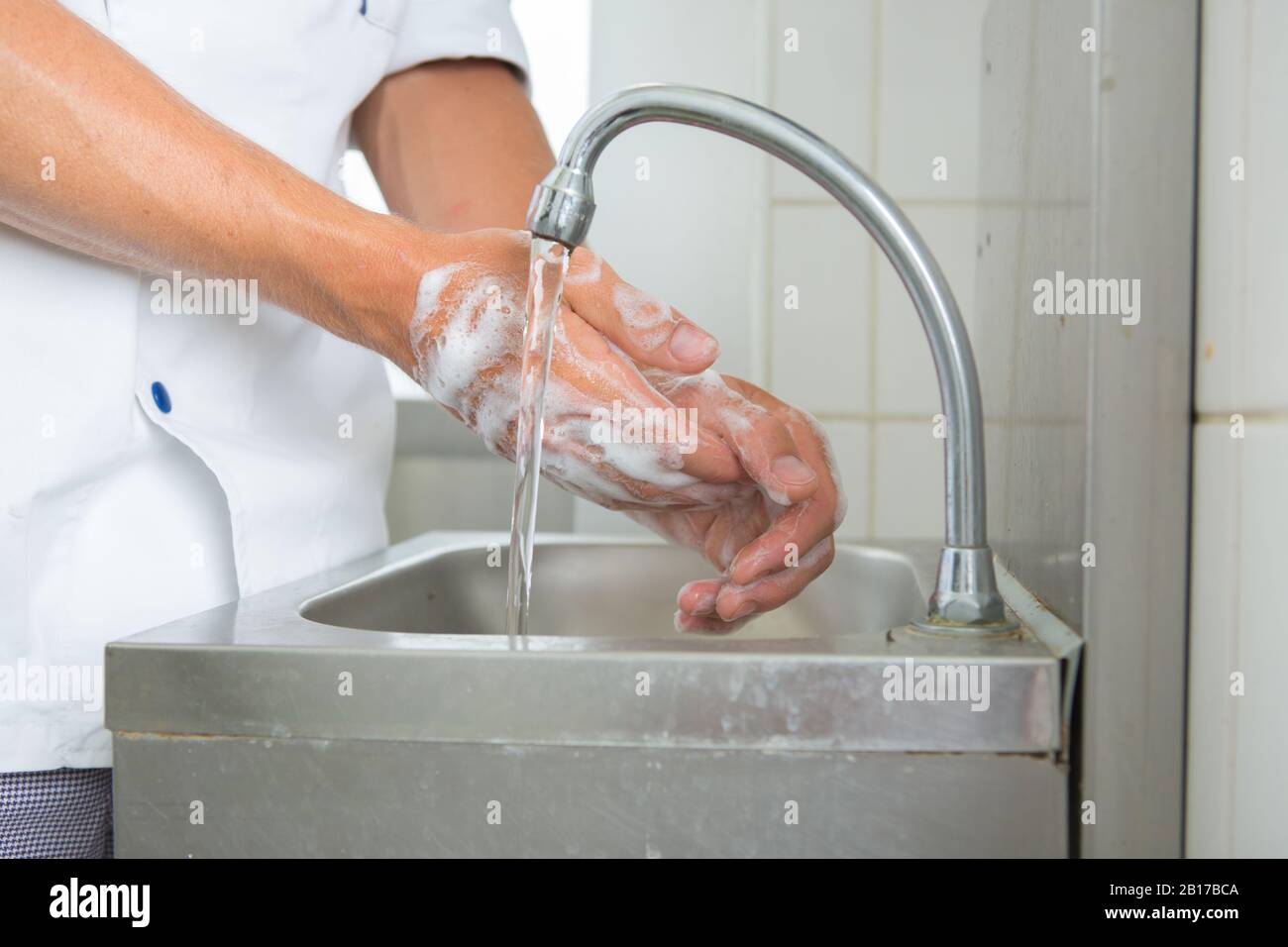 Koch wascht seine Hände in der gewerblichen Küche Stockfoto