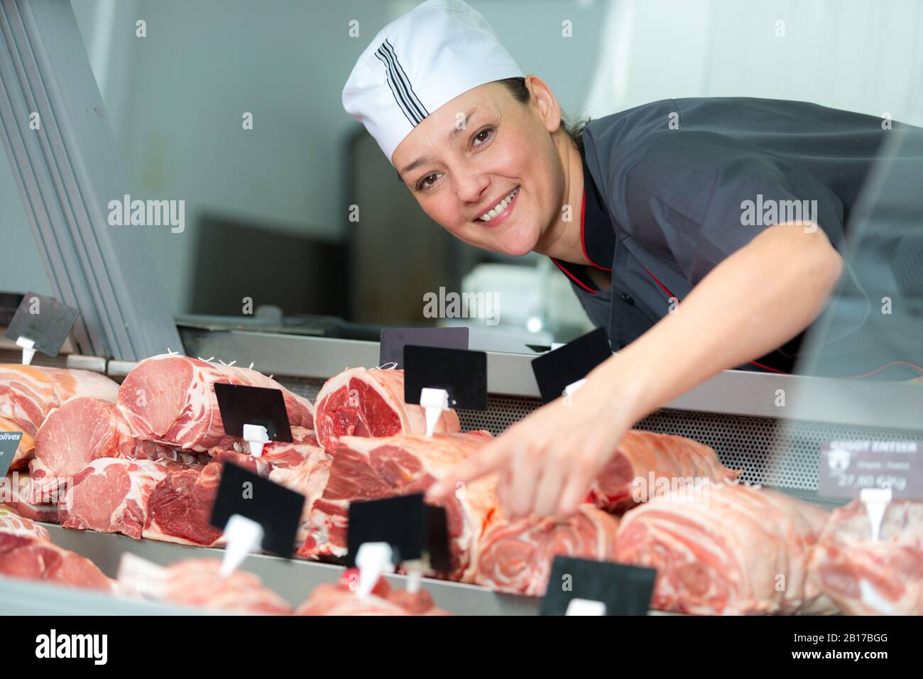 weibliche Metzger in Fleisch Ladentheke Stockfoto