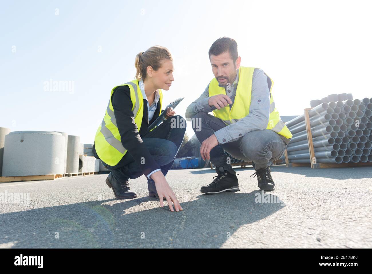 Mann und Frau untersuchen Asphalt im Materialhof Stockfoto