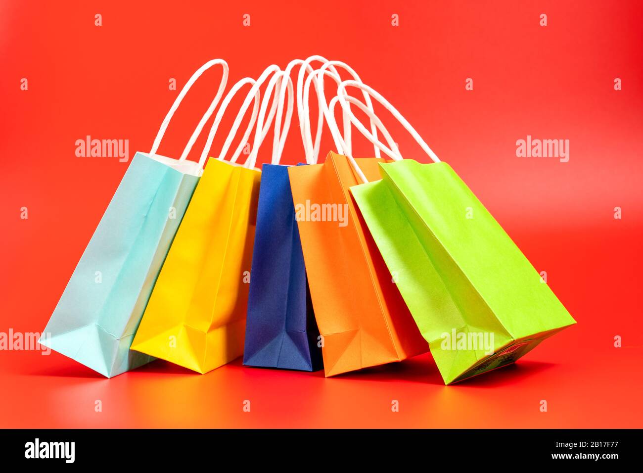 Bunte Einkaufs- oder Geschenkbeutel isoliert auf Rot Stockfoto