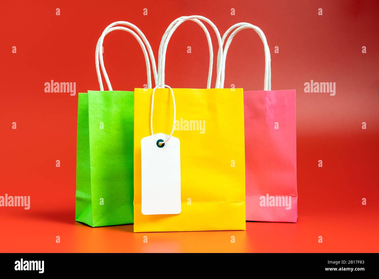 Gelbe, grüne und rosafarbene Einkaufs- oder Geschenkbeutel isoliert auf Rot Stockfoto