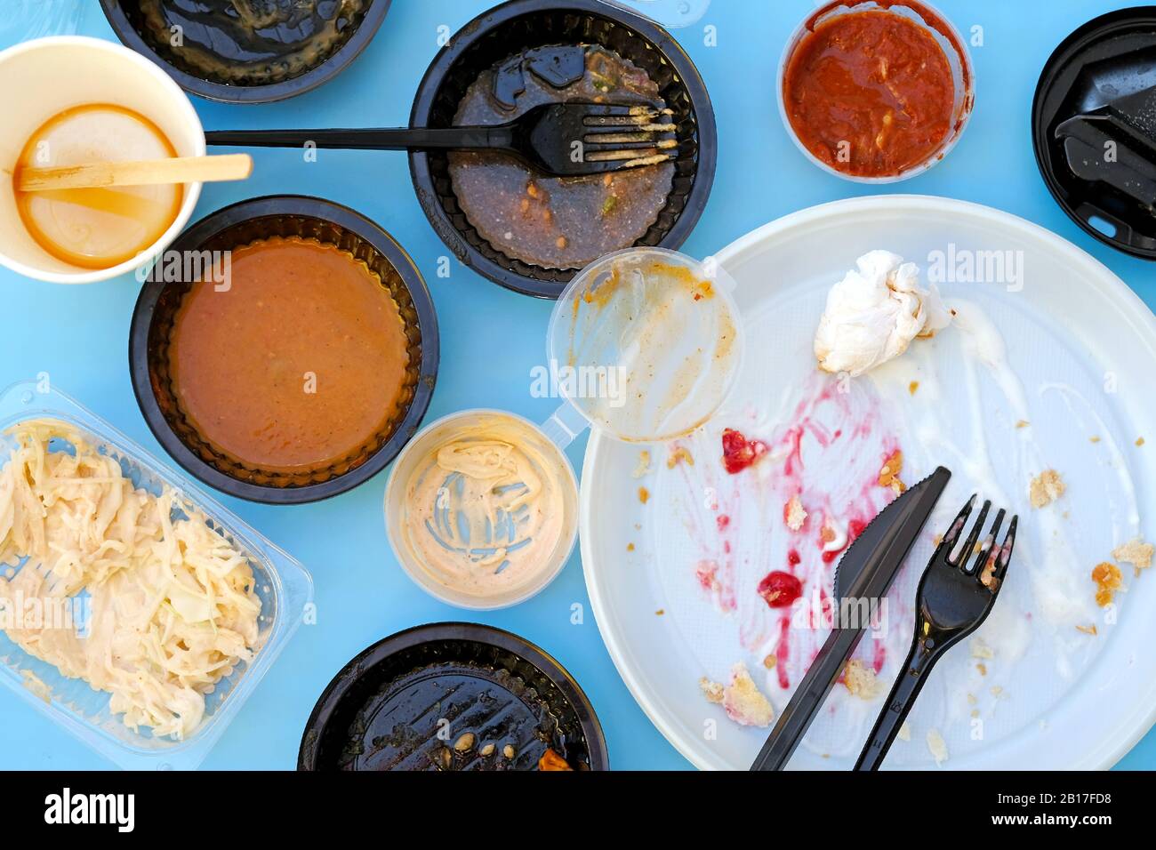 Leere schmutzige Plastikgerichte nach dem Abendessen. Gebrauchte Kunststoffschalen, Draufsicht. Teller, Schüsseln, Gabeln und ein Messer aus Kunststoff nach Gebrauch. Schnelles Mittagessen in einer fas Stockfoto