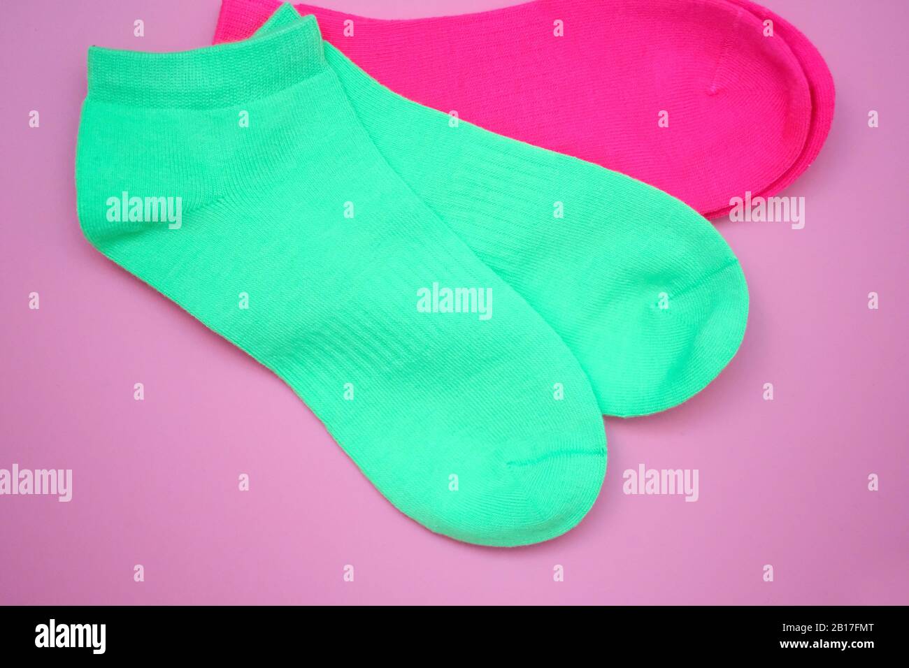 Sport Socken hellgrün Draufsicht. Helle Damensocken auf pinkfarbenem Hintergrund. Niedrige Socken aus natürlicher Baumwolle. Stockfoto