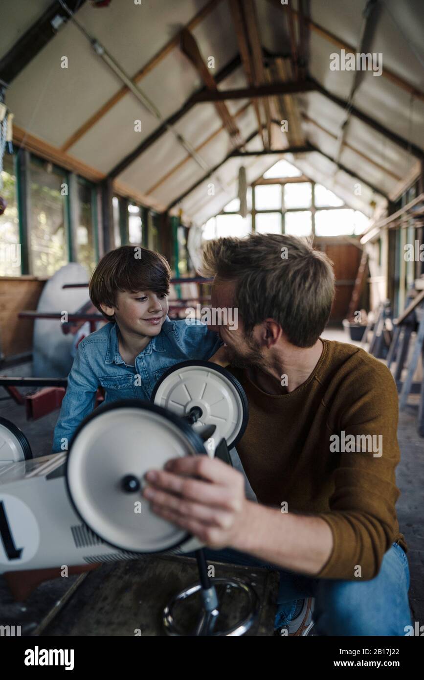 Vater und Sohn reparieren Spielzeugauto in der Scheune Stockfoto