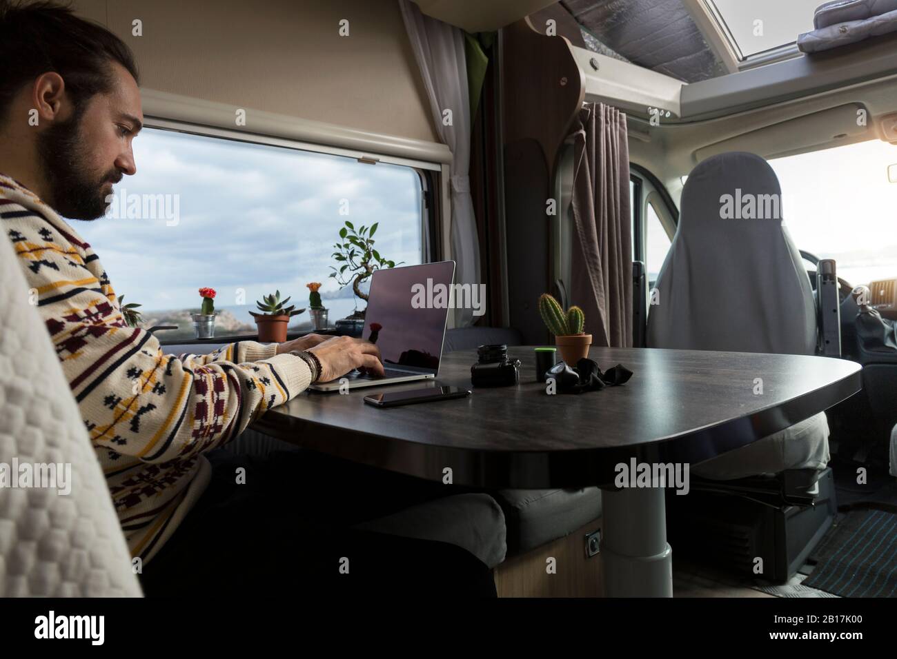 Mann, der auf einem Laptop in seinem Wohnmobil arbeitet, Es Mercadal, Menorca, Spanien Stockfoto