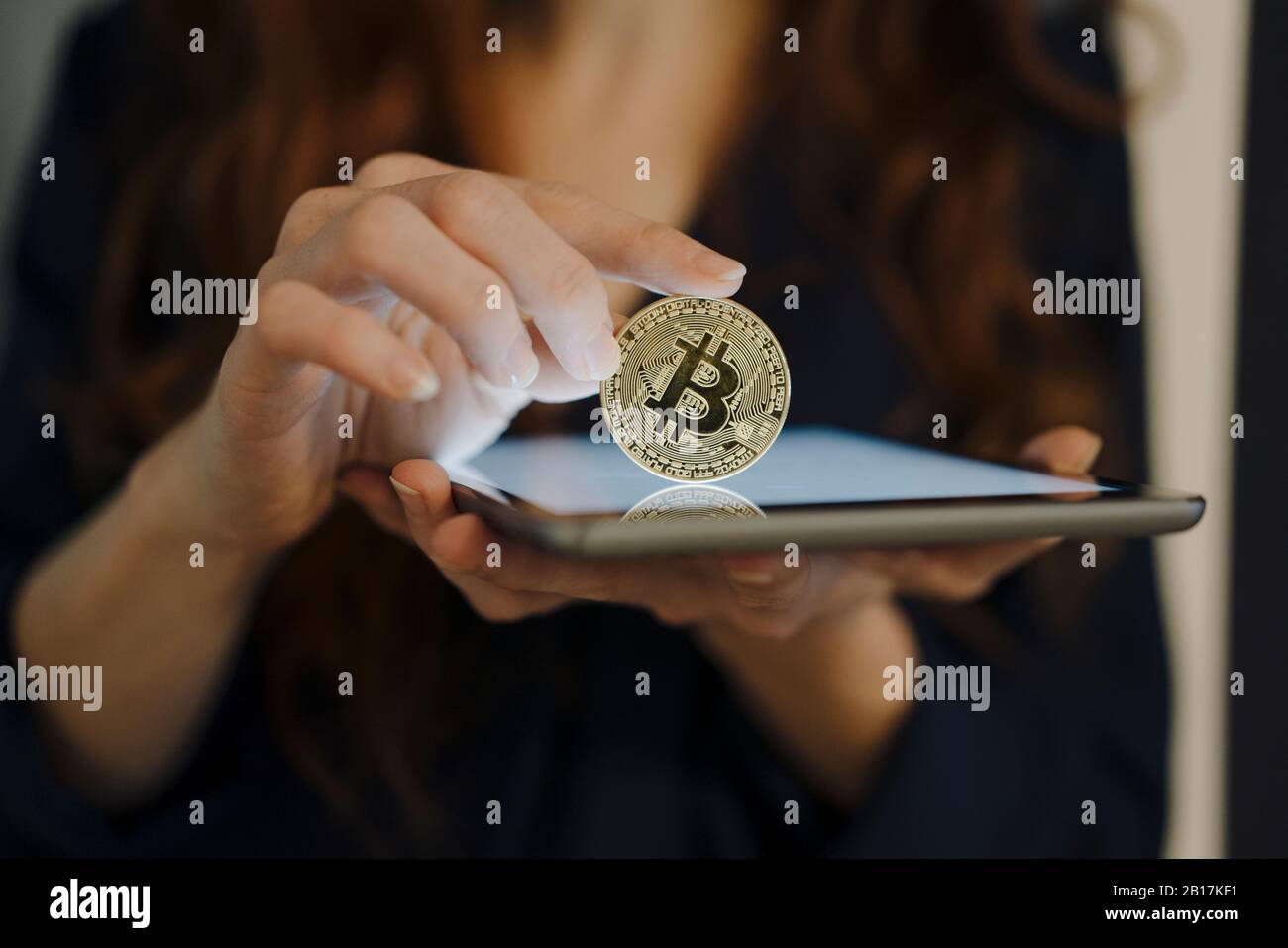 Nahaufnahme der Frau, die Bitcoin und Tablette hält Stockfoto