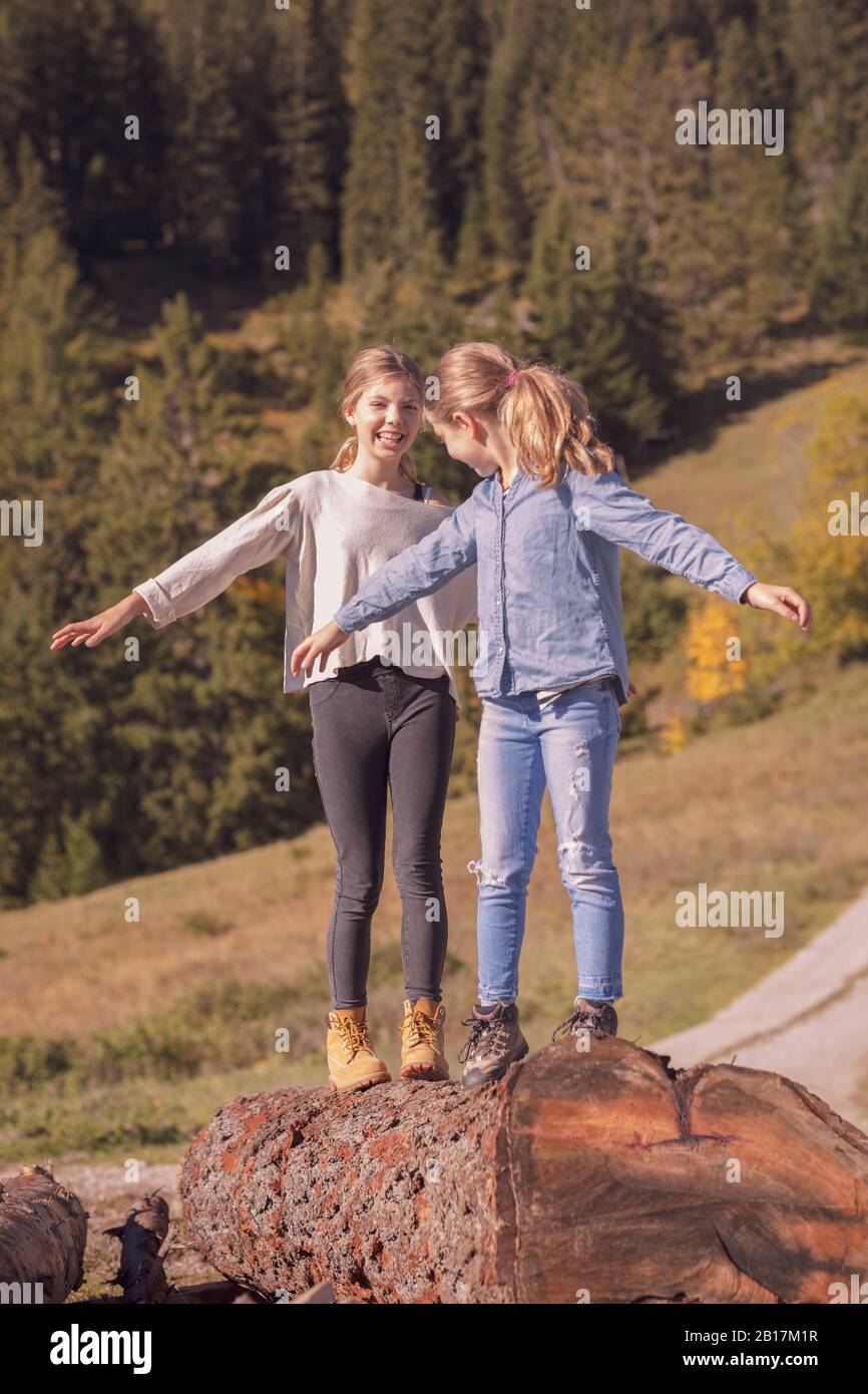 Zwei junge Mädchen balancieren auf einem Baumstamm Stockfoto