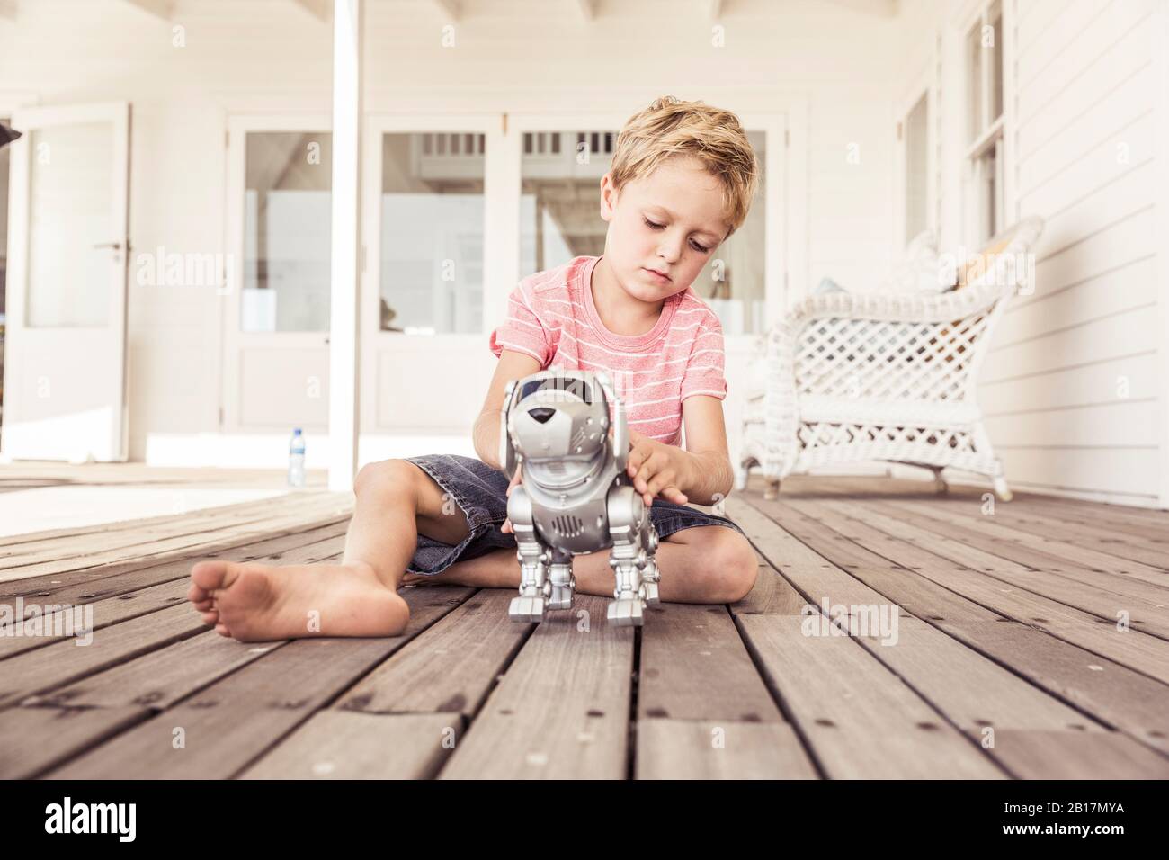 Junge spielt mit Roboter Hund auf der Veranda Stockfoto