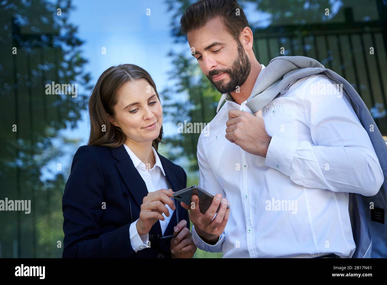 Geschäftsmann und Geschäftsfrau, die auf das Handy in der Stadt schaut Stockfoto