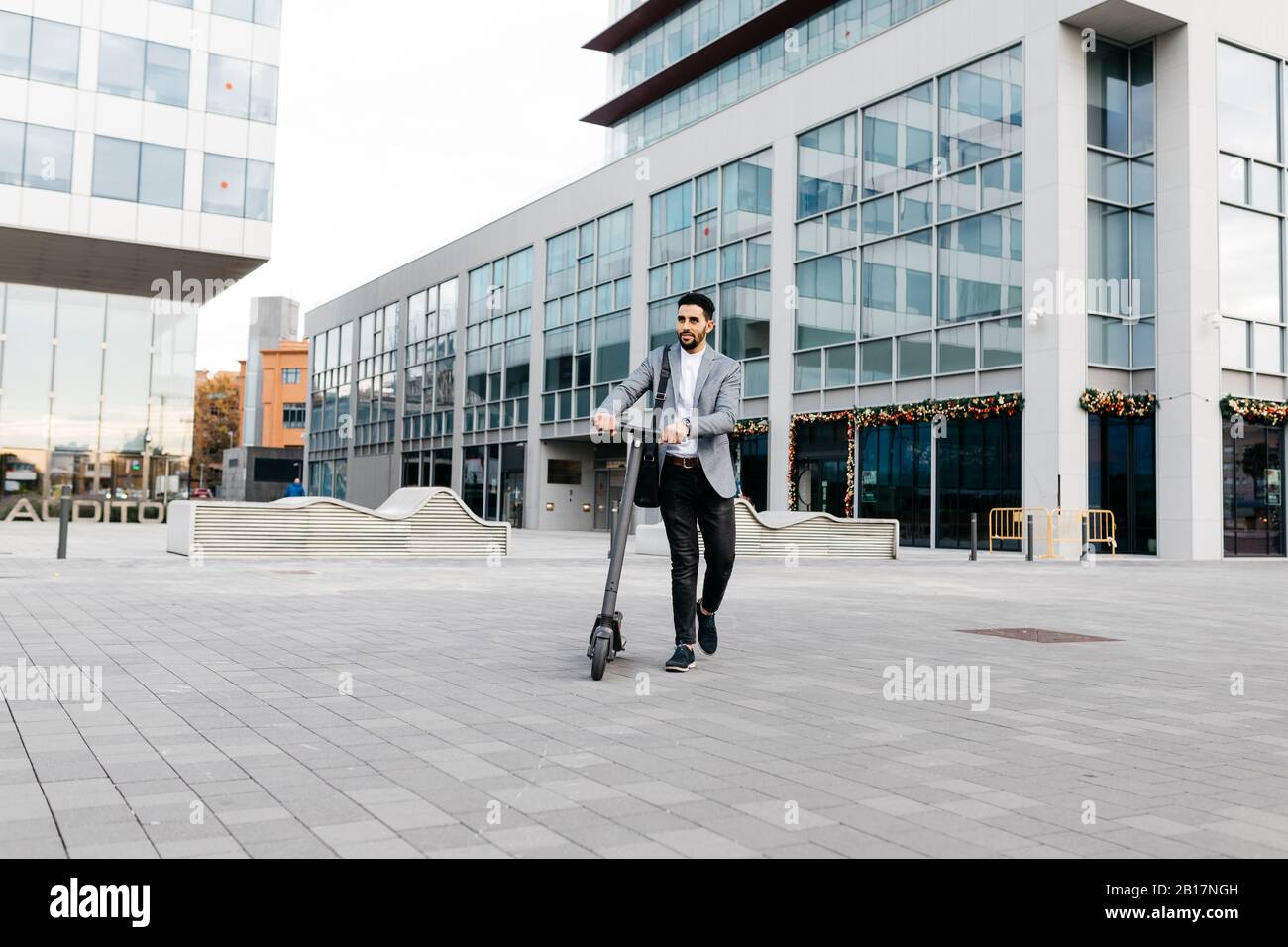 Legerer junger Geschäftsmann, der Elektro-Roller in der Stadt treibt Stockfoto