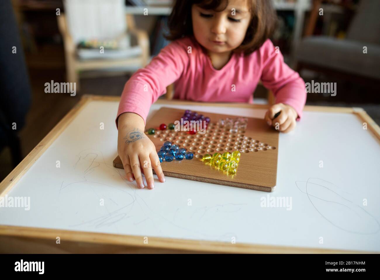 Kleines Mädchen spielt mit Murmeln auf dem Tisch Stockfoto