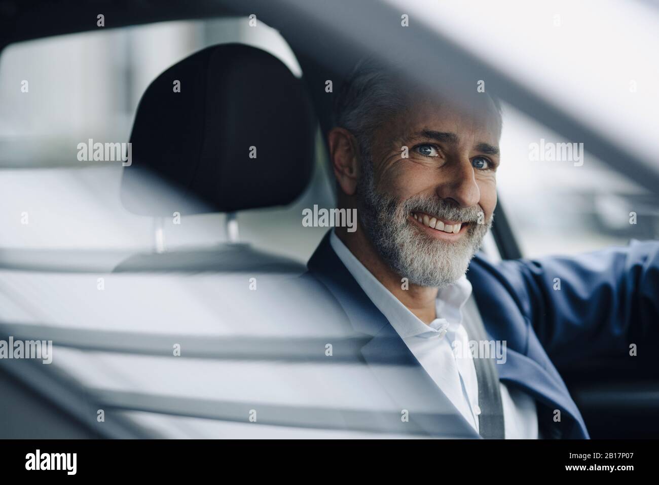 Porträt eines lächelnden reifen Geschäftsmannes in seinem Auto Stockfoto