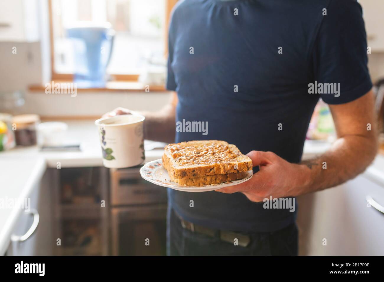 Nahaufnahme des Menschen in der Küche mit Sandwiches und einem Becher Stockfoto