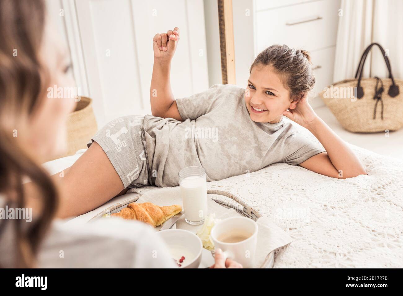 Porträt von lächelndem Mädchen mit Frühstück mit ihrer Mutter auf dem Bett Stockfoto