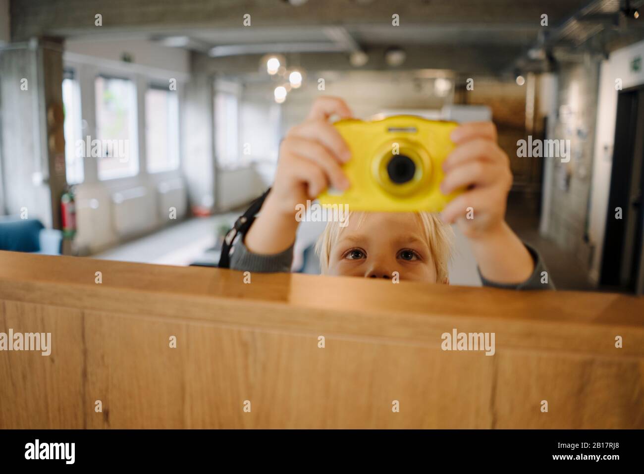 Junge, die mit einer Kamera im Büro ein Foto machen Stockfoto