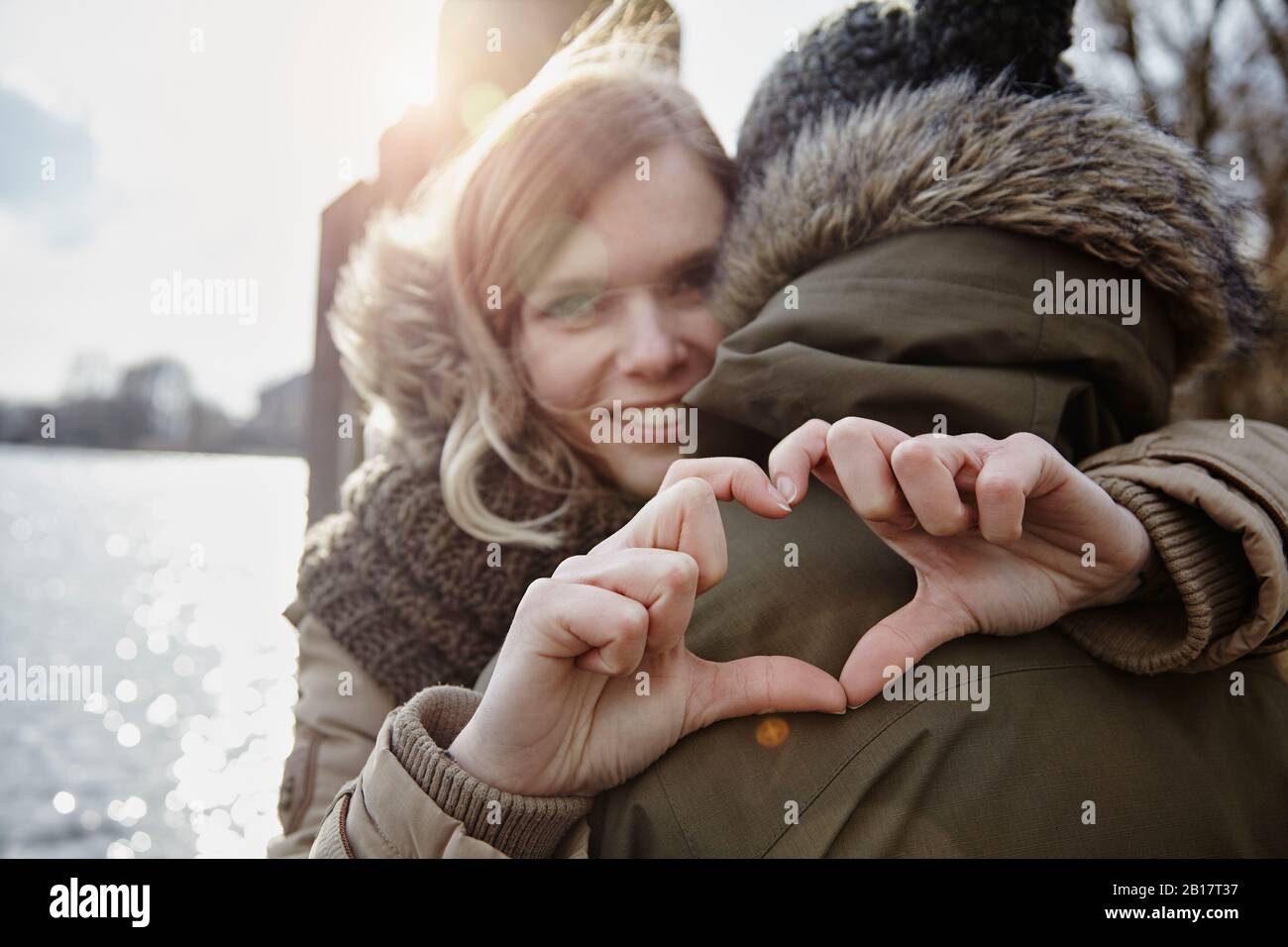 Glückliche junge Frau, die mit ihren Händen Herz bildet Stockfoto