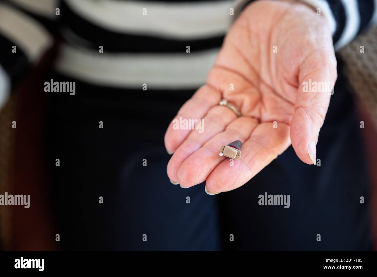 Die Hand der älteren Frau mit modernem Hörgerät Stockfoto