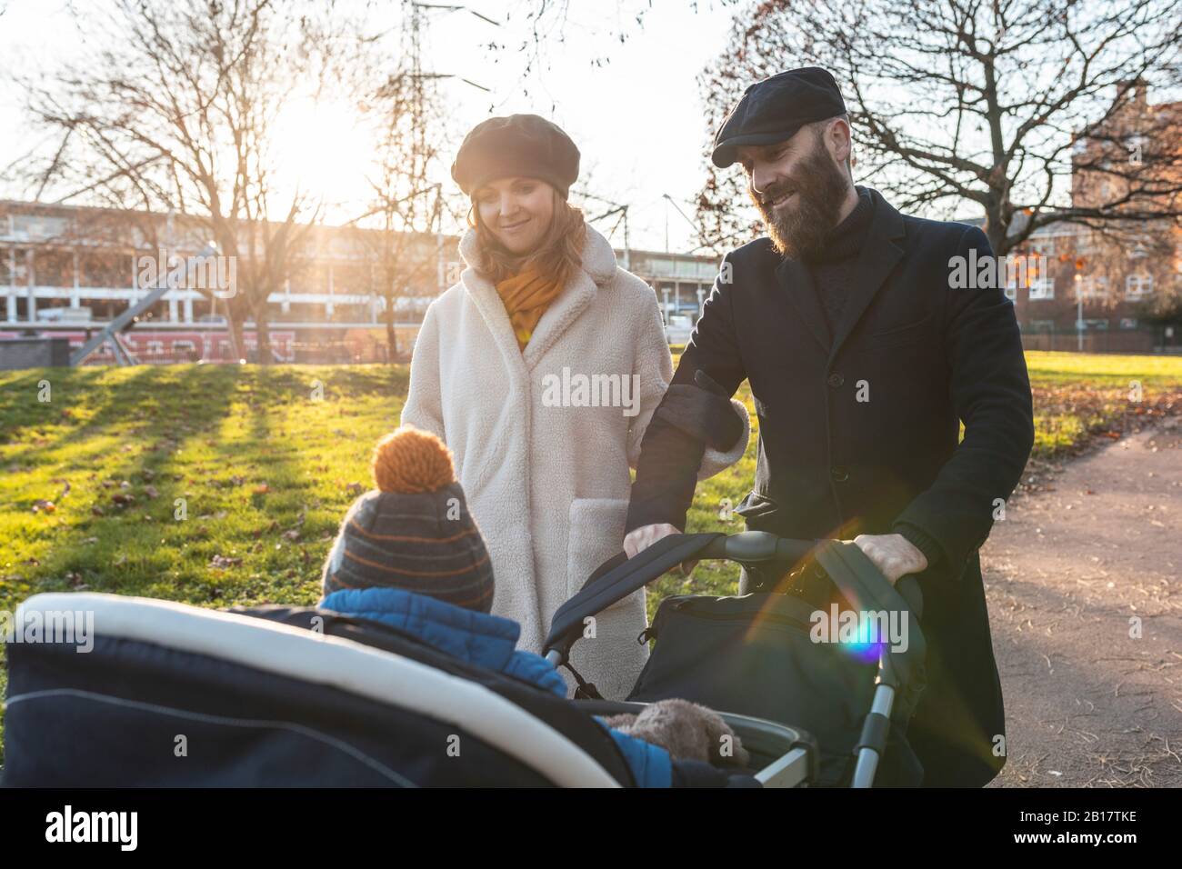 Glückliches Paar mit kleinem Sohn in einem Kinderwagen im Park Stockfoto