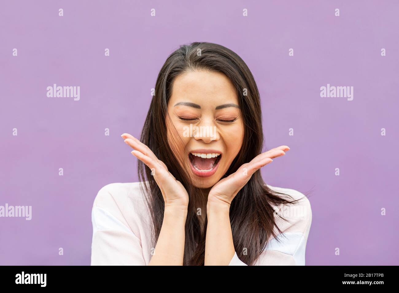 Porträt von glücklichen Frau mit geschlossenen Augen weinend vor Freude vor lila Hintergrund Stockfoto