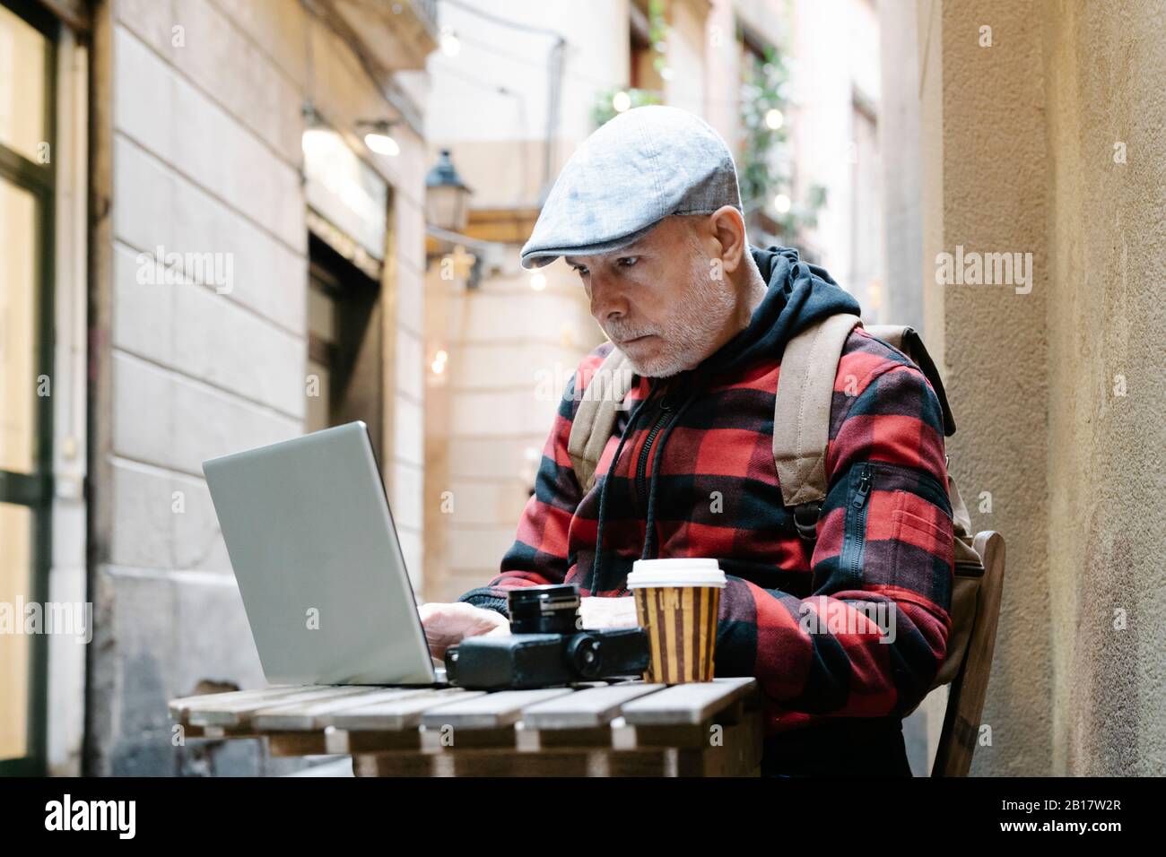 Porträt eines älteren Mannes, der in einem Straßencafé mit Laptop sitzt, Barcelona, Spanien Stockfoto