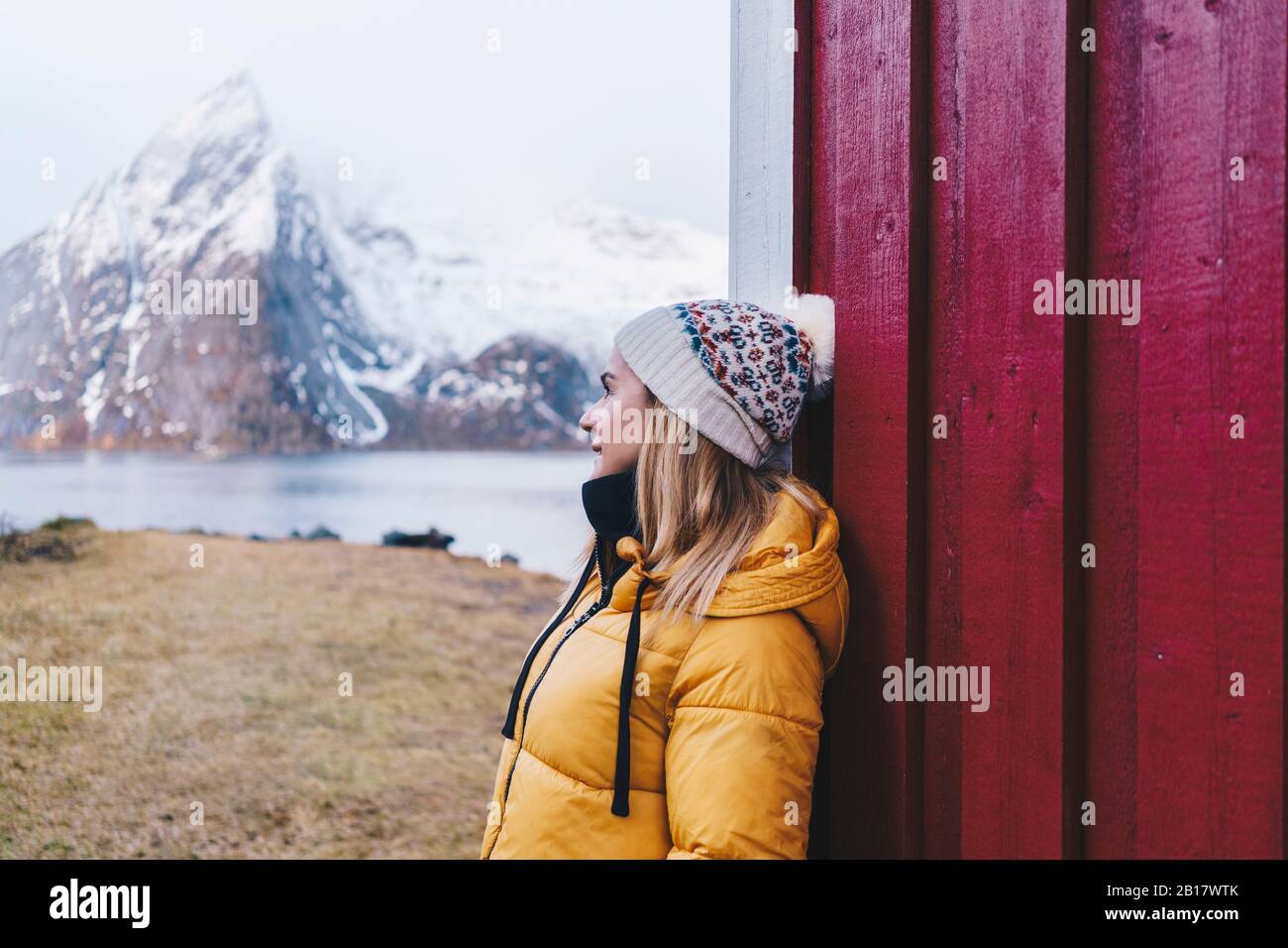 Lächelnder Tourist lehnt eine Hütte in Hamnoy, Lofoten, Norwegen ab Stockfoto